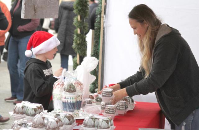 Ginger Wiggins, right, shows off some treats as Braden Deal takes it all in at the Czech Christmas Market